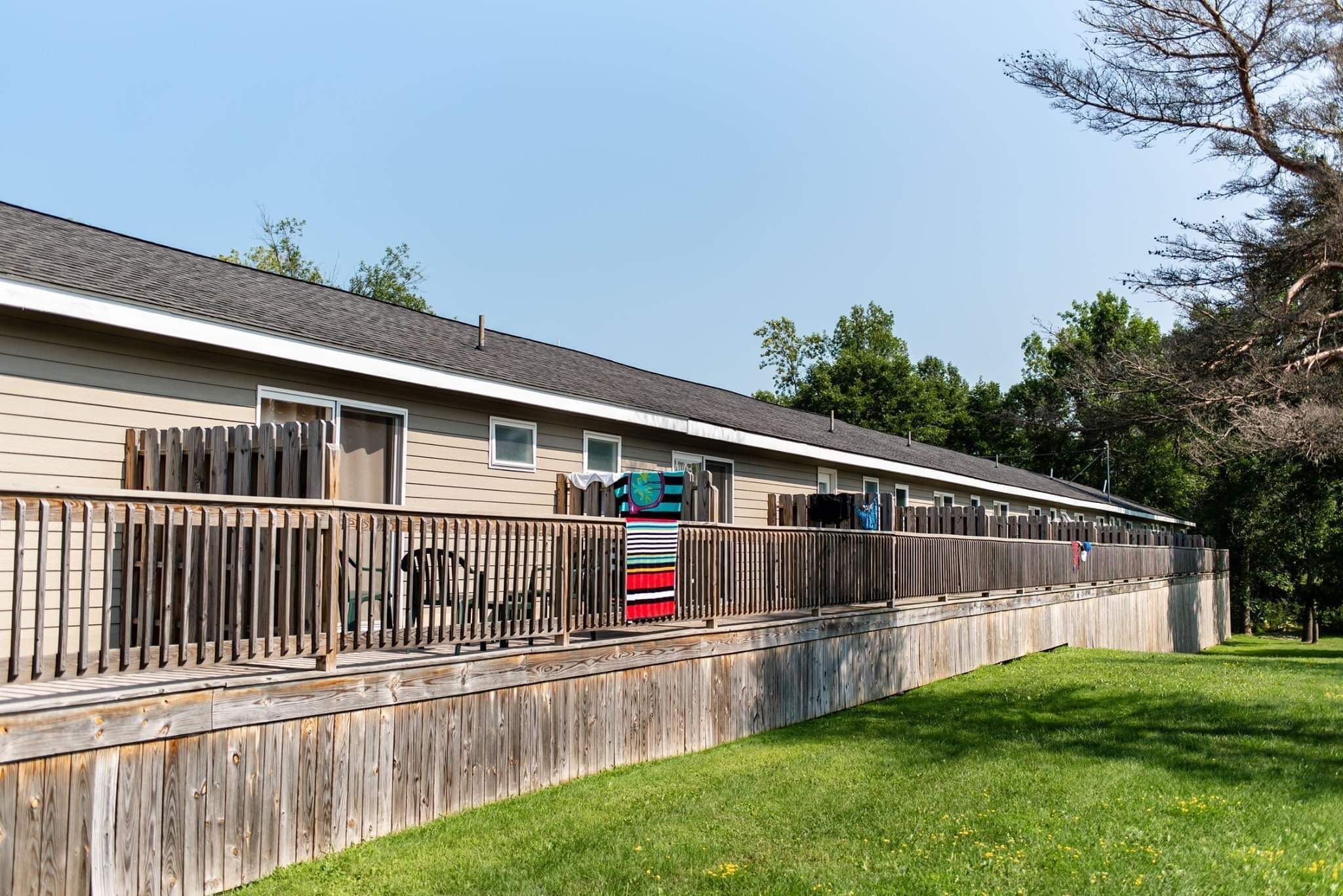 A long, single-story building with a wooden fence and a grassy area in front.