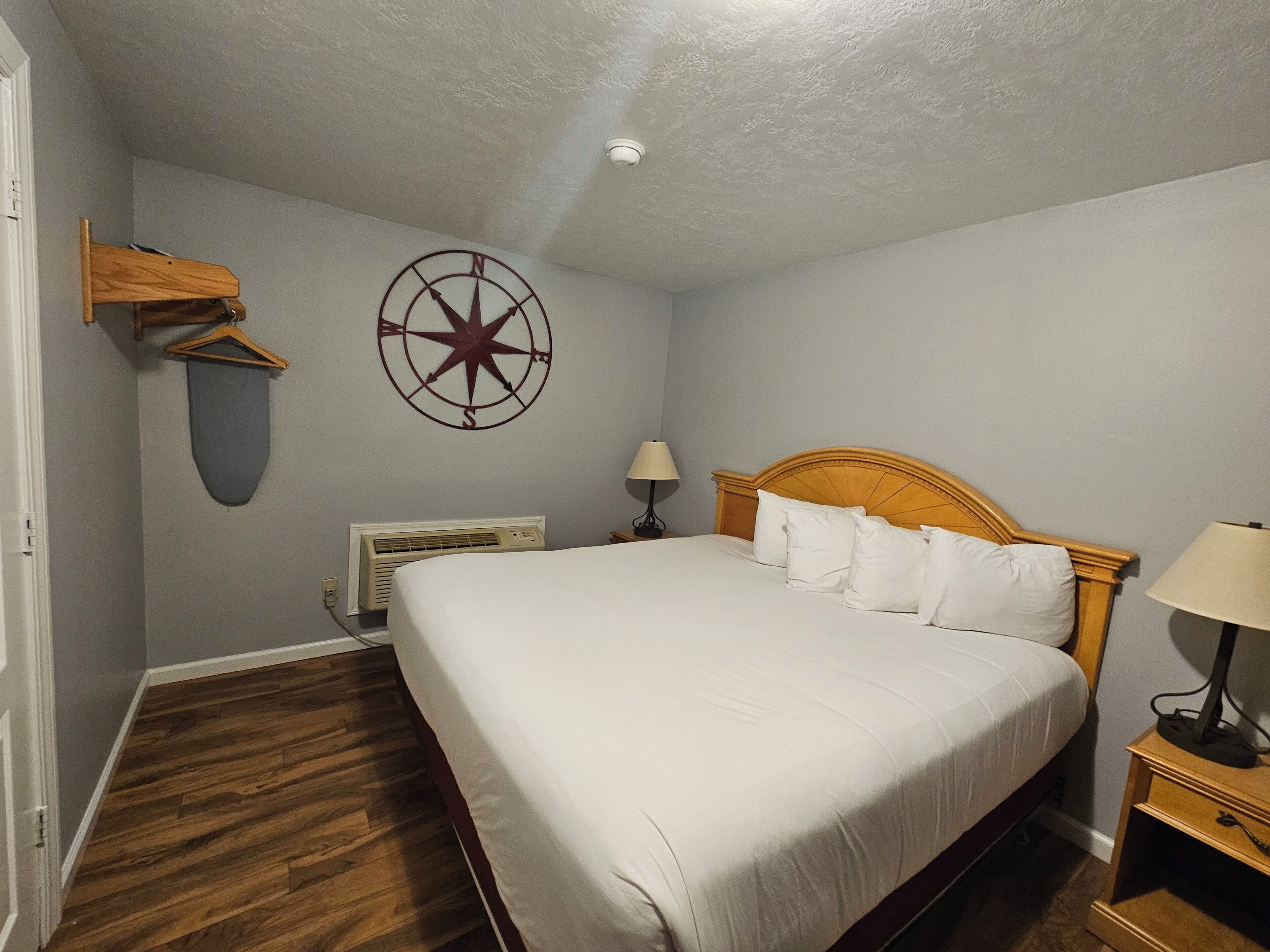 A bedroom with a wooden bed, a wall-mounted heater, and a compass decoration.