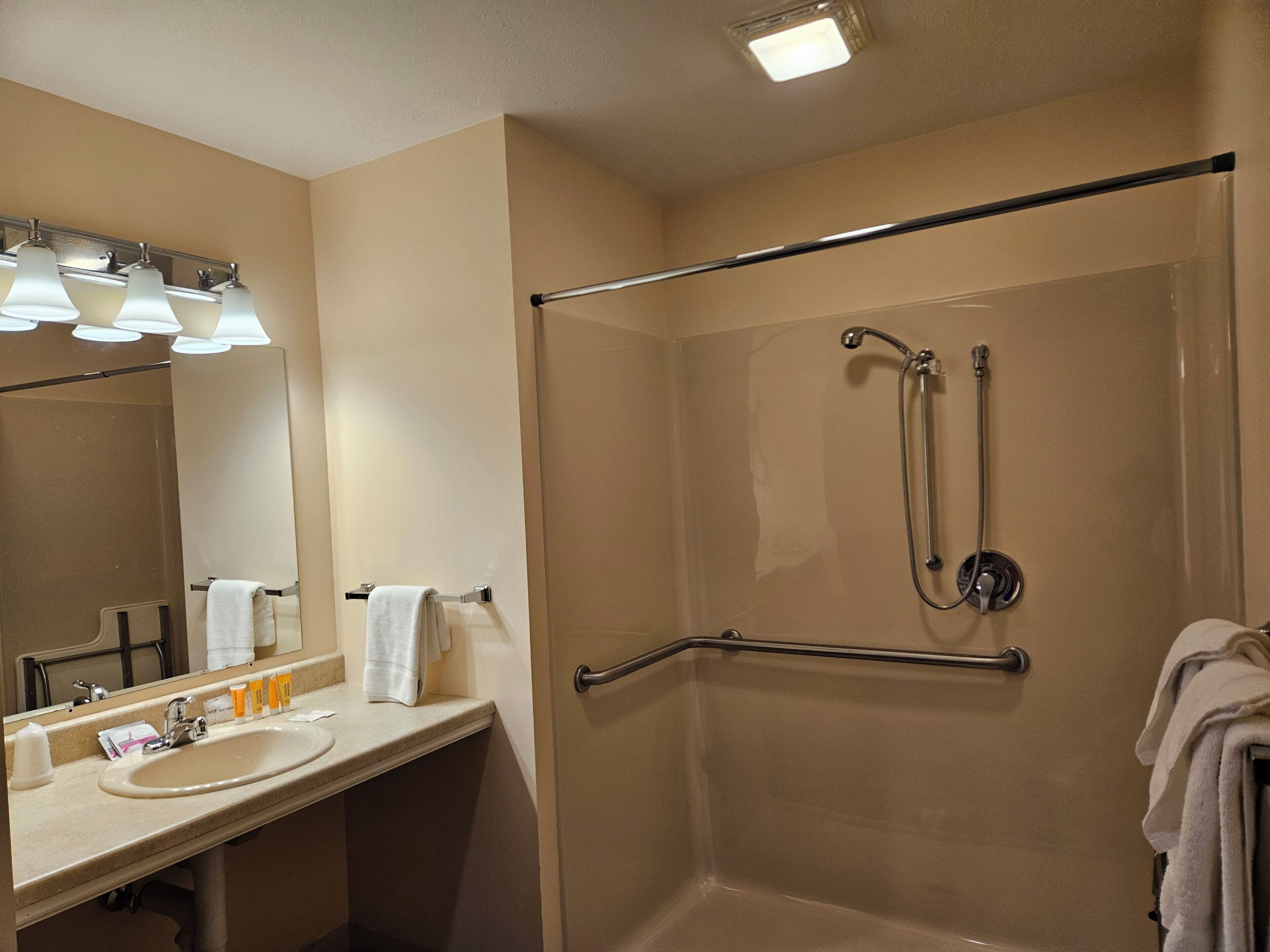 Une salle de bain d’hôtel avec un lavabo, un miroir et une douche.