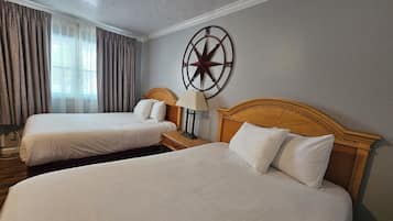 Ein Hotelzimmer mit zwei Betten, einem Holz-Kopfteil, einer Wanduhr und einem Fenster mit Vorhängen.