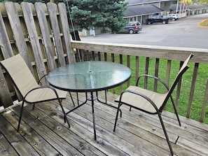 A wooden deck with a glass table and two chairs.