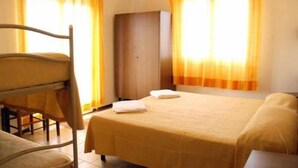 A room with a bed, a wooden chair, a wardrobe, and curtains.