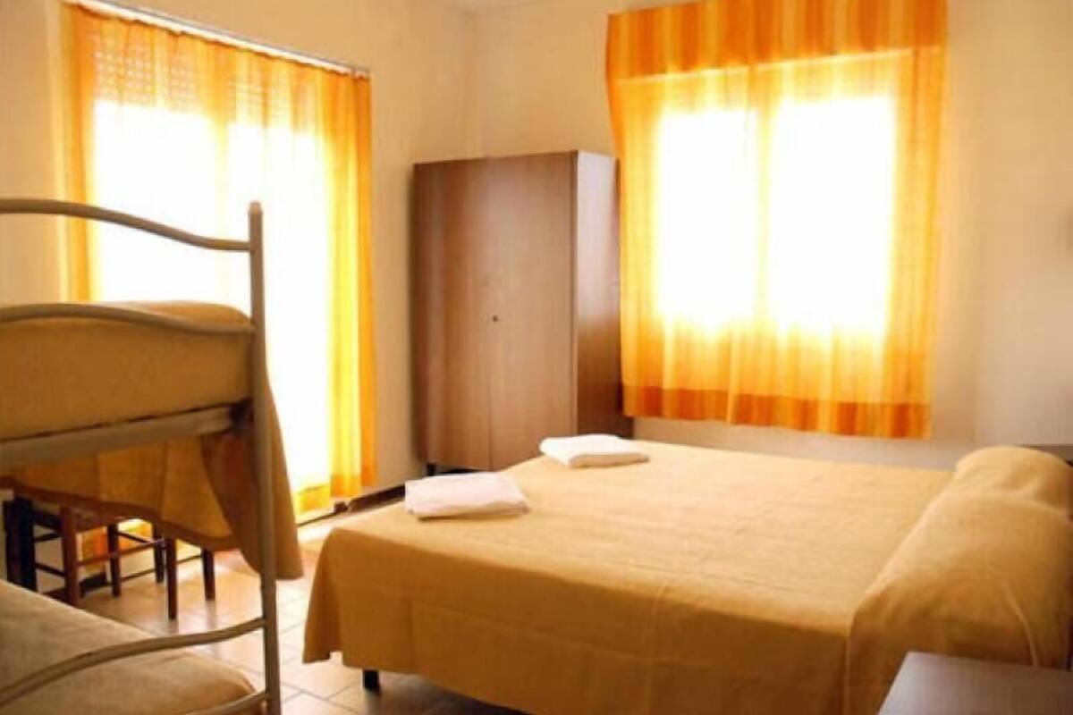Een kamer met een bed, een houten stoel, een garderobe en gordijnen.