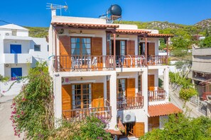 Un edificio de dos pisos con balcones, una antena parabólica y vistas a una ladera.
