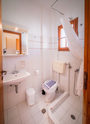 Un baño con lavamanos, inodoro y ducha blancos.