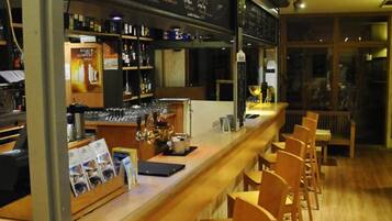 Angolo bar con un bancone in legno, sgabelli e lavagna dei menu.
