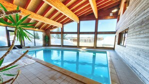 Une piscine avec des poutres en bois et de grandes fenêtres.