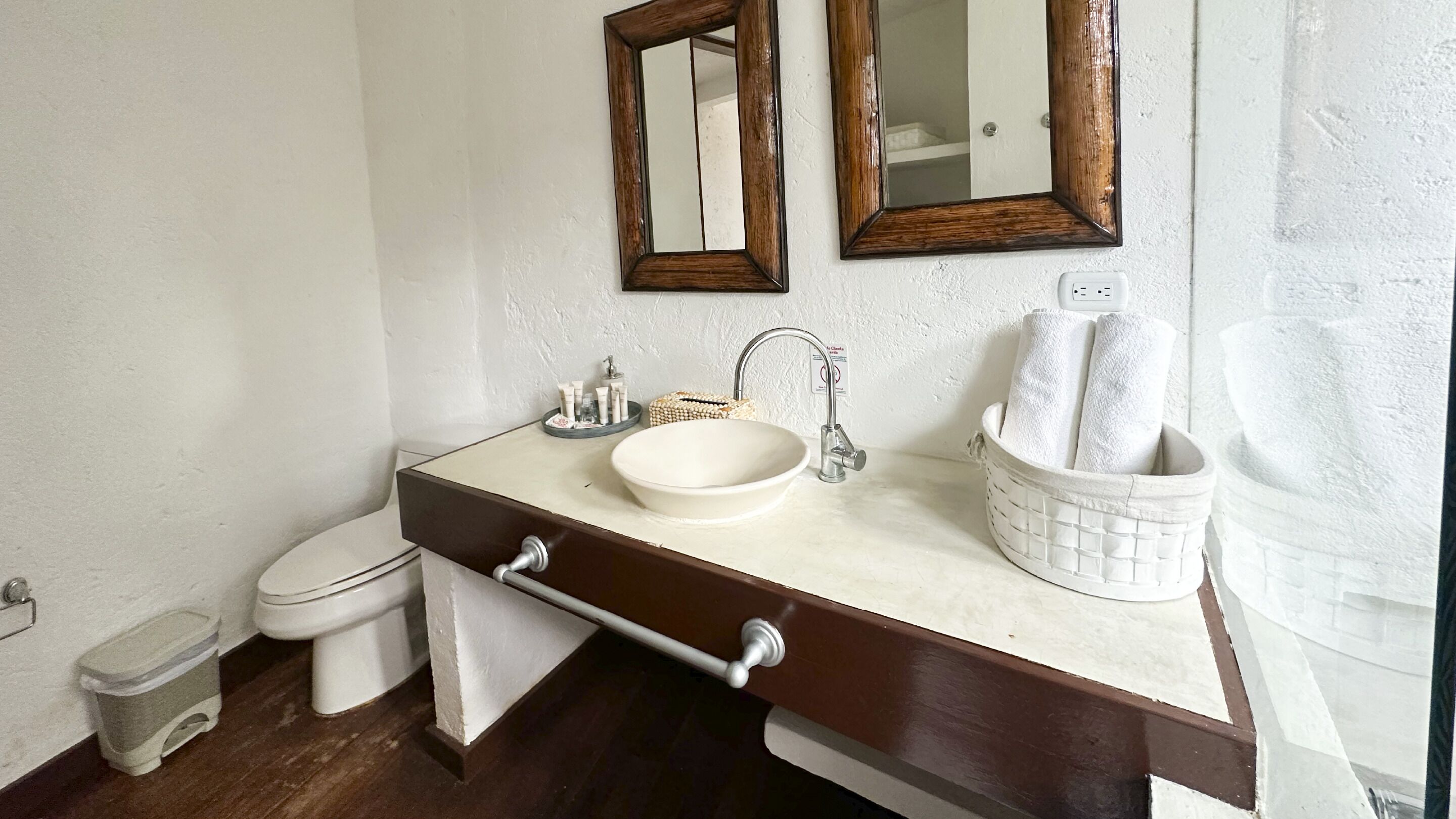 A bathroom with a white sink, a mirror, a towel holder, and a toilet.