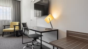 A hotel room with a desk, chair, and bed.