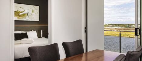 Una habitación de hotel moderna con una cama, una mesa de comedor y vista a un cuerpo de agua.