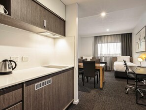 A hotel room with a kitchenette, a dining area, a bed, and a window with curtains. - Mercure Sunshine Coast Kawana Waters (Birtinya)