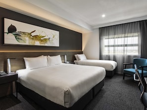 A hotel room with a large bed, a smaller bed, a desk with a lamp, a chair, and a window with curtains. - Mercure Sunshine Coast Kawana Waters (Birtinya)