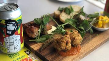 Uma refeição com pão, vegetais e uma lata sobre uma tábua de madeira.