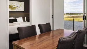A modern hotel room with a bed, a dining table, and a view of a body of water. - Mercure Sunshine Coast Kawana Waters (Birtinya)