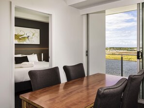 A modern hotel room with a bed, a dining table, and a view of a body of water. - Mercure Sunshine Coast Kawana Waters (Birtinya)