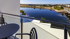 A balcony with a table and chairs overlooking a calm body of water and a distant cityscape. - Mercure Sunshine Coast Kawana Waters (Birtinya)