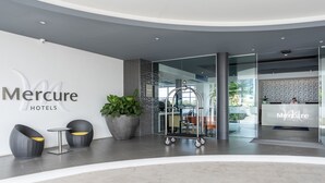 A modern hotel lobby with a reception desk, seating area, and potted plants. - Mercure Sunshine Coast Kawana Waters (Birtinya)