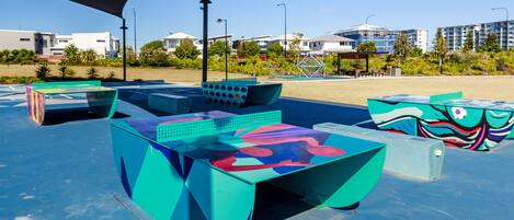 An outdoor seating area with colorful, modern furniture under a shaded structure.