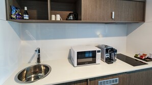 Eine moderne Küche mit einer Edelstahl-Spüle, einer Mikrowelle, einer Kaffeemaschine und einem Wasserkocher auf der Arbeitsfläche.