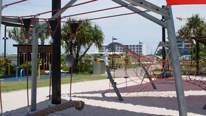 Ein Spielplatz mit Schaukeln, Klettergerüsten und einer Hängebrücke.