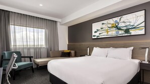 A hotel room with a large bed, a desk, a chair, a window with curtains, and a wall-mounted abstract painting. - Mercure Sunshine Coast Kawana Waters (Birtinya)