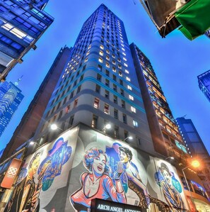 A tall building with a mural of two figures on its facade. - Madera Hollywood (Hong Kong)