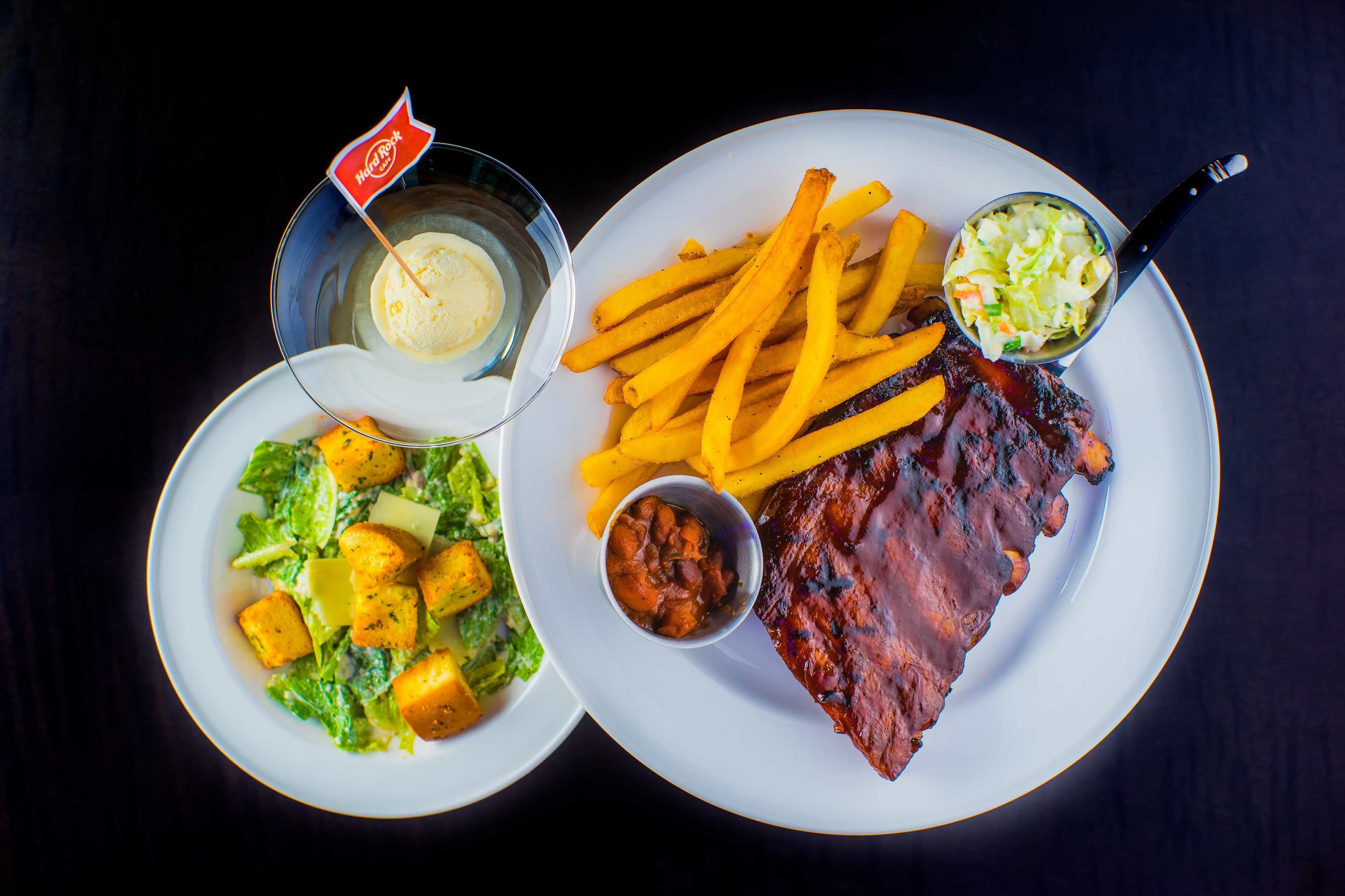 A plate with a steak, fries, coleslaw, and a salad with cubed potatoes.