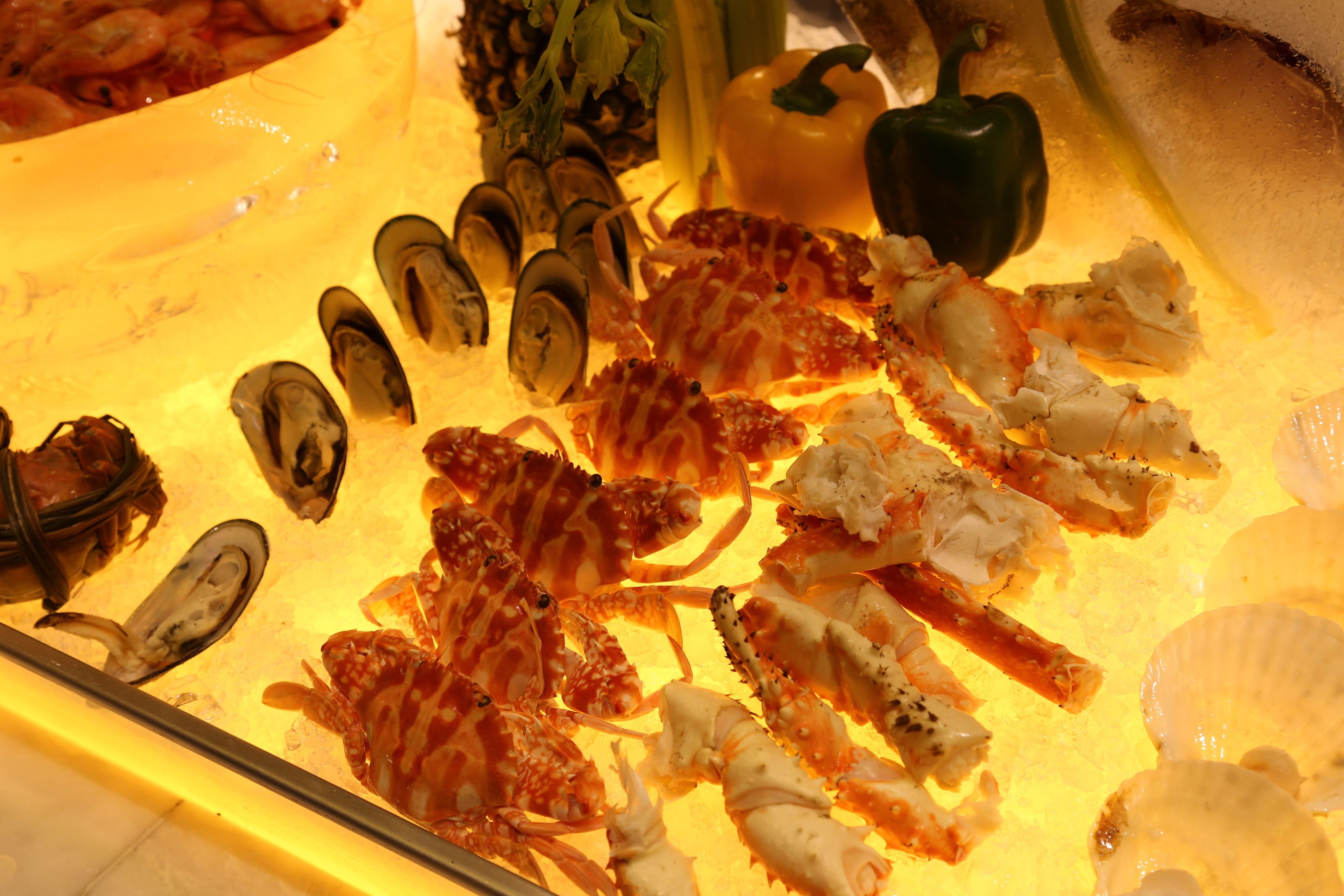 A seafood display with various shellfish and a bell pepper.
