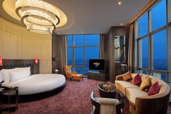 Una habitación de hotel con una cama grande, un sofá, un televisor y vistas a la ciudad.
