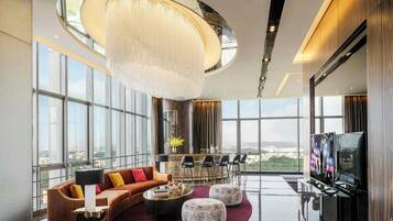 A spacious living room with a large chandelier, a sofa set, a bar area, and a television.