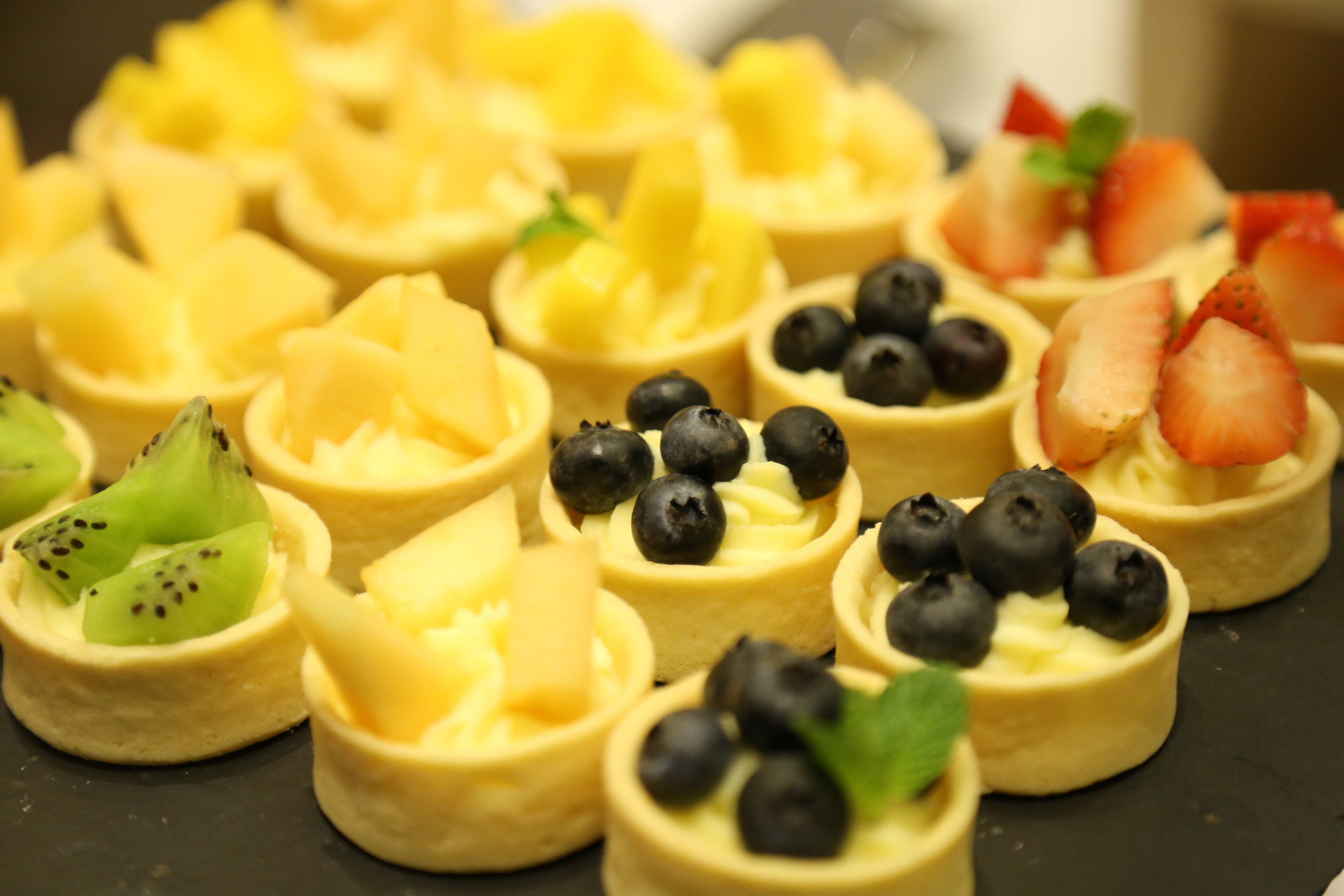 A variety of fruit tarts arranged on a tray.