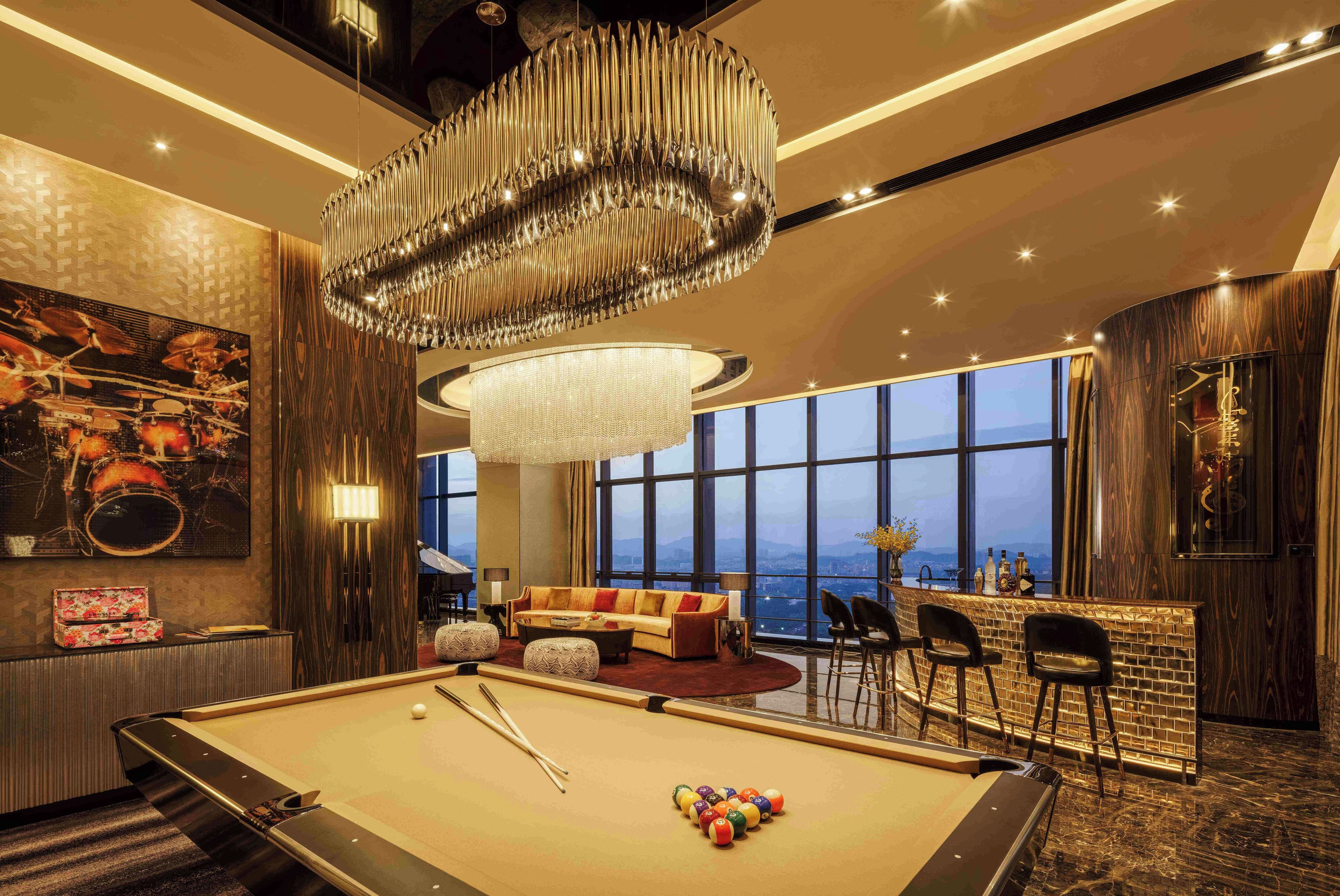 Quarto luxuoso com mesa de bilhar, um lustre grande e vista para a cidade.
