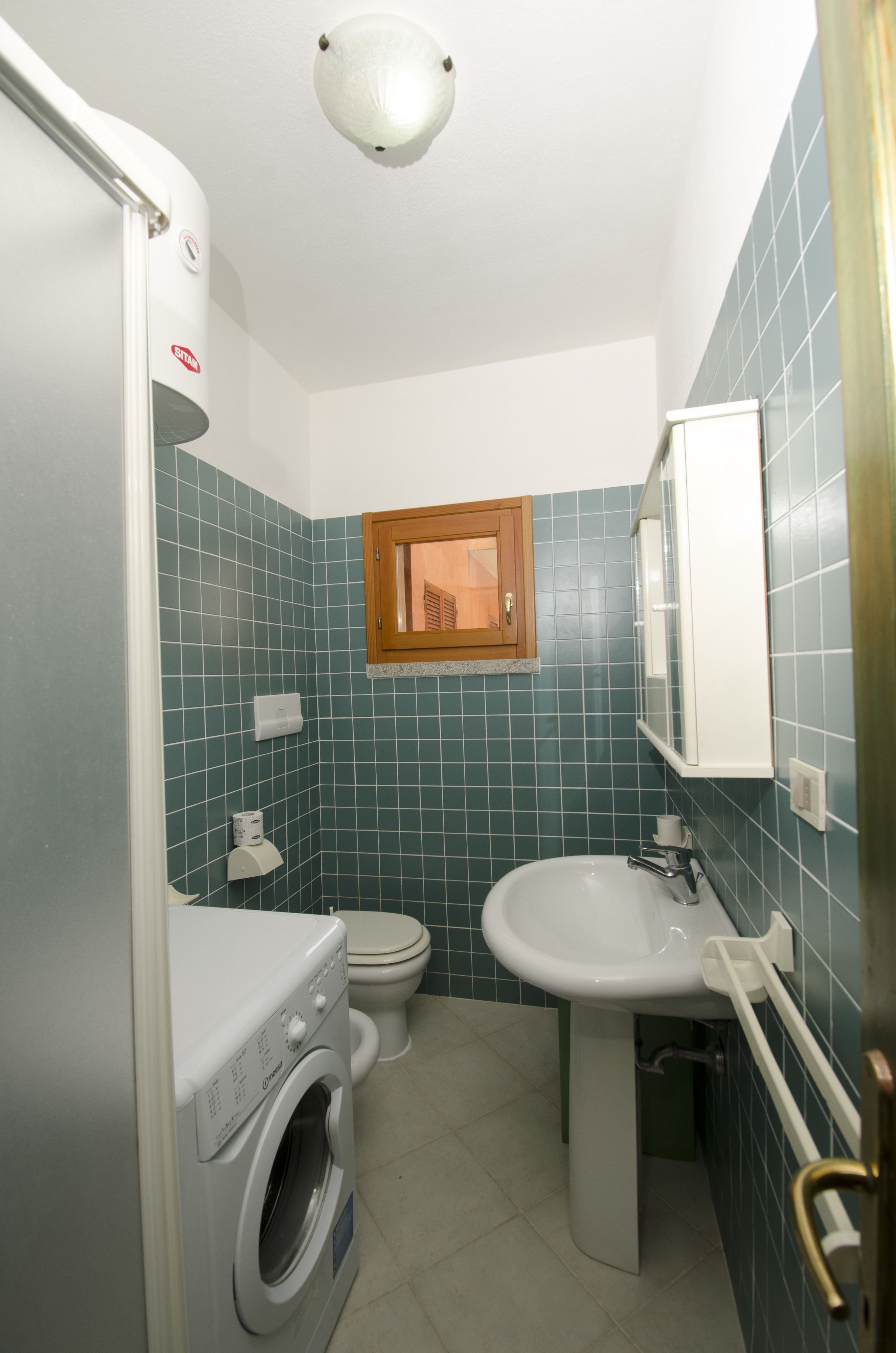 Un baño pequeño con lavadora, inodoro y lavabo.