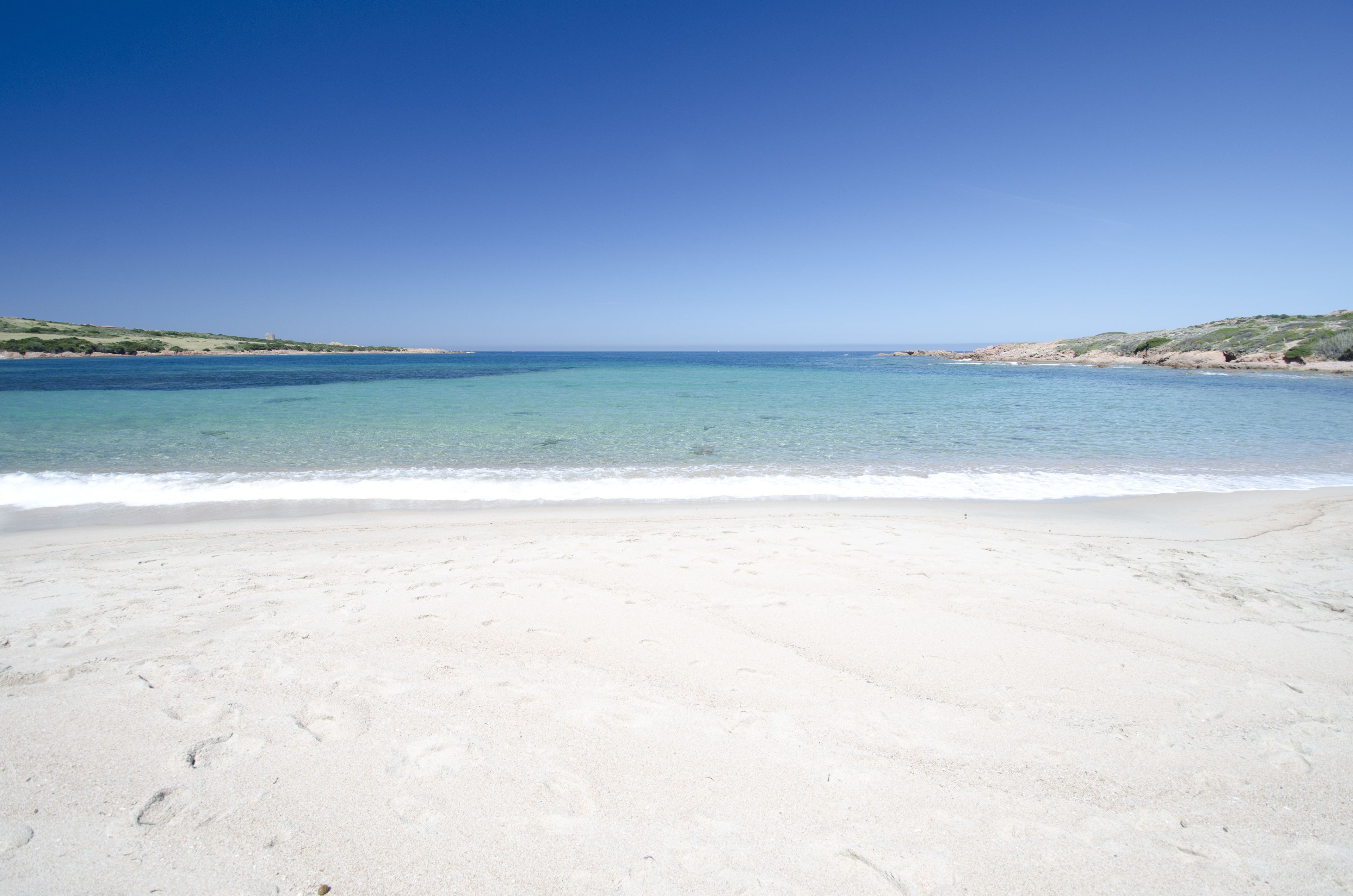 Una playa con agua azul cristalina y arena blanca.