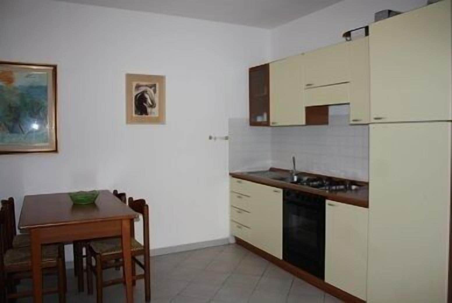 Una cucina compatta con un tavolo da pranzo e sedie, un piccolo armadietto e un quadro appeso al muro.