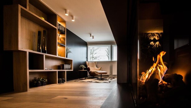 A modern living room with a fireplace, wooden shelving, and a comfortable chair. - Wellness Hasselt Bed & Breakfast (Hasselt)