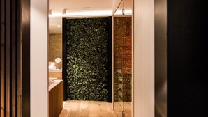 A modern hallway with wooden flooring, a green leafy wall, and a glass door leading to a room. - Wellness Hasselt Bed & Breakfast (Hasselt)
