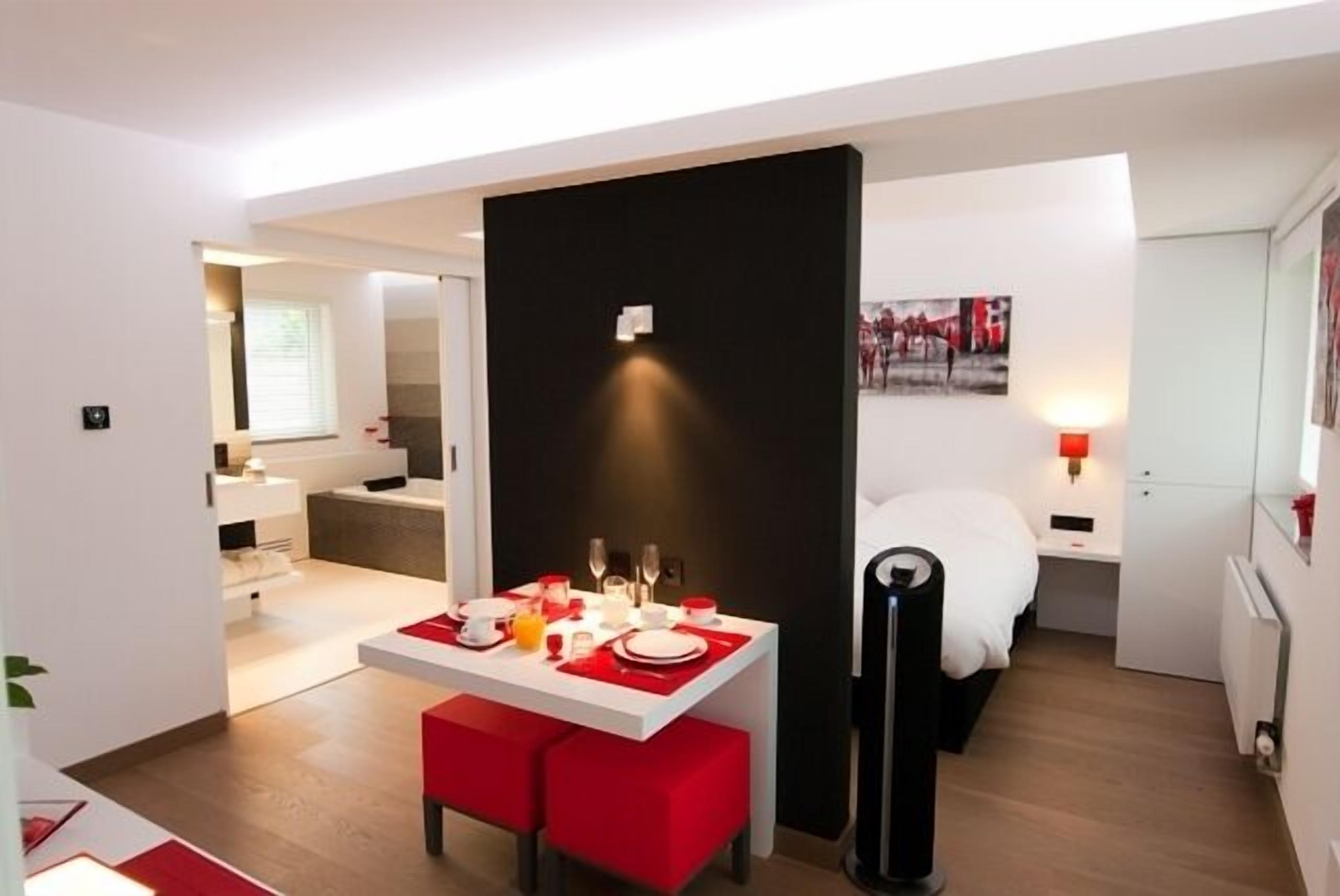 A modern hotel room with a dining area, a bed, and a bathroom.