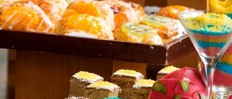 Variedad de postres en una mesa de buffet, incluyendo pasteles, productos de pastelería y un postre en capas en vaso.