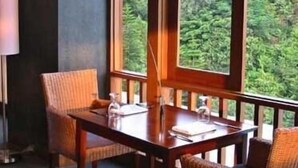 A room with a wooden table and wicker chairs, large windows with a view of greenery outside. - SanGria Resort & Spa (Lembang)
