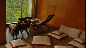 A room with a large window, a wooden floor, and a seating area with cushions and a chair. - SanGria Resort & Spa (Lembang)