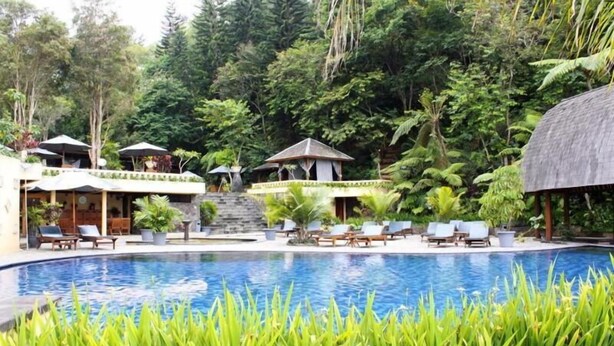 A pool surrounded by lush greenery, with lounge chairs and a gazebo. - SanGria Resort & Spa (Lembang)