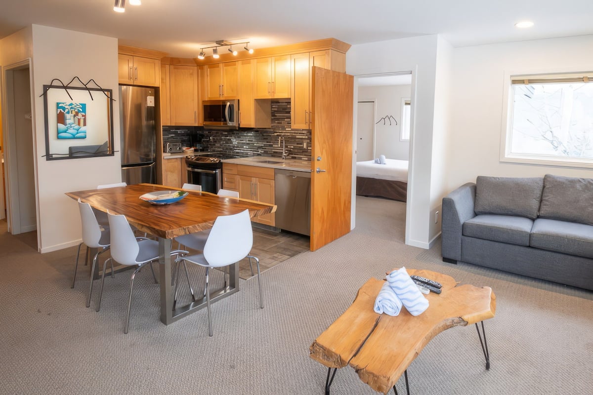 A modern kitchen with wooden cabinets and a dining area with a wooden table and white chairs.