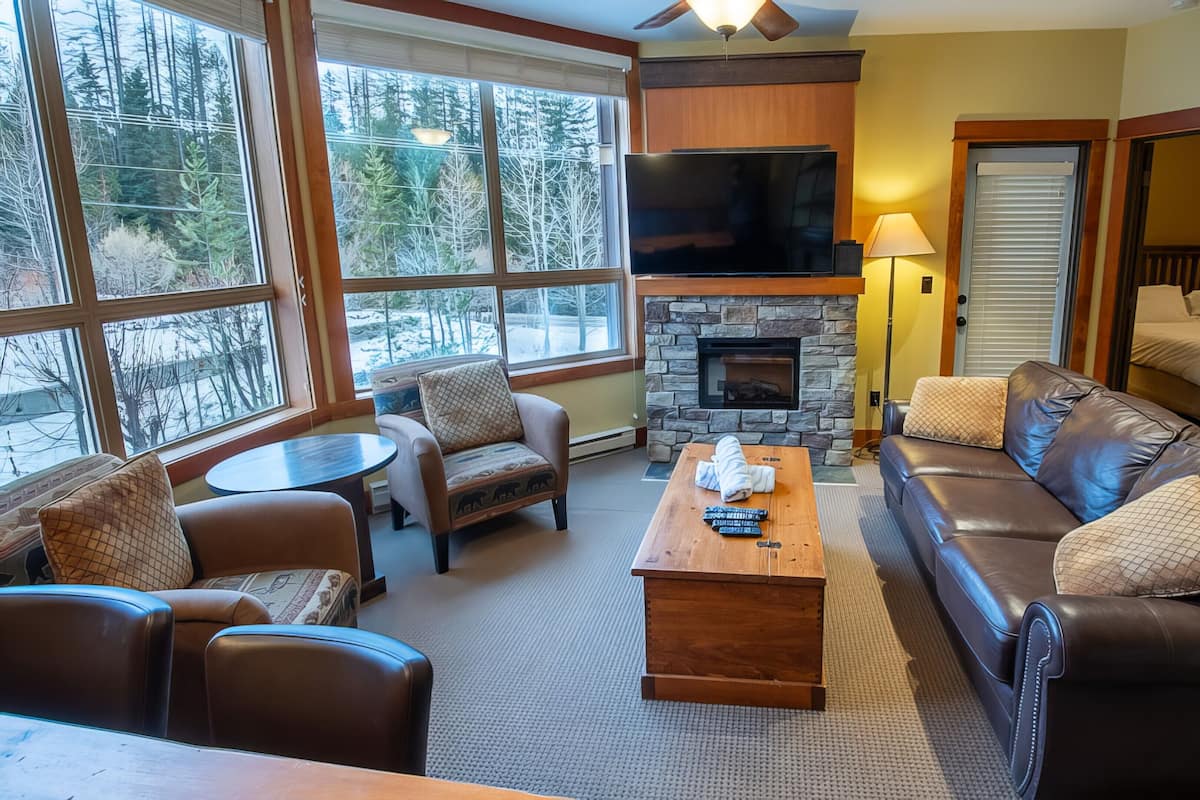 A cozy living room with a stone fireplace, leather sofas, and a flat-screen TV.