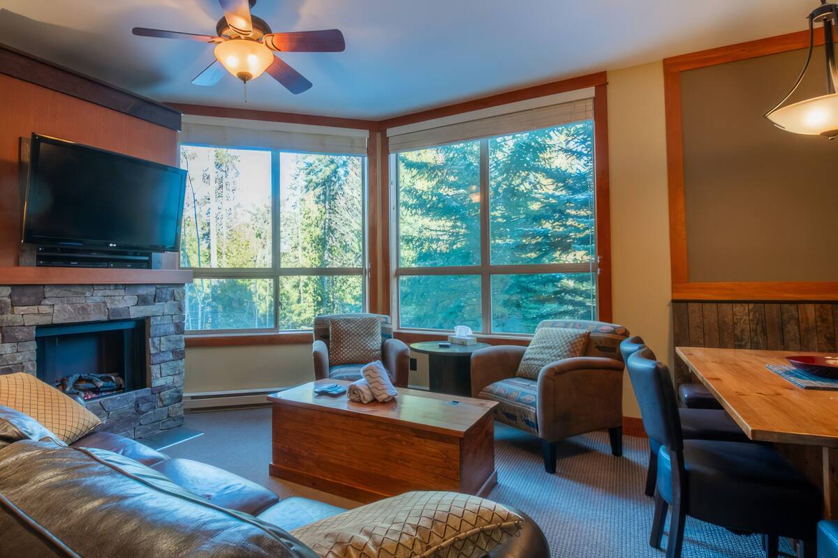 A cozy living room with a stone fireplace, leather sofa, and a television.