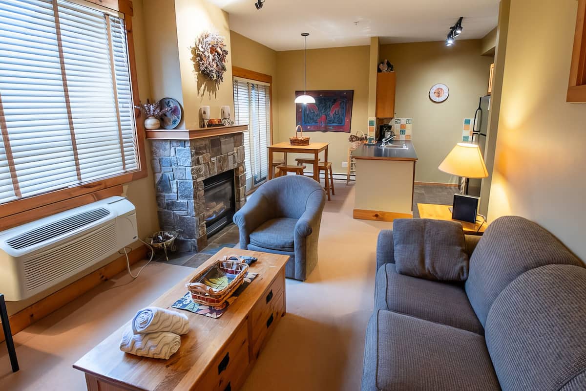 A cozy living room with a fireplace, a dining area, and a kitchen.