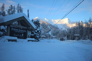 Paisaje nevado de montaña con un letrero que dice 'Fernie Lodging Company' y 'King First Spa & Wellness'.