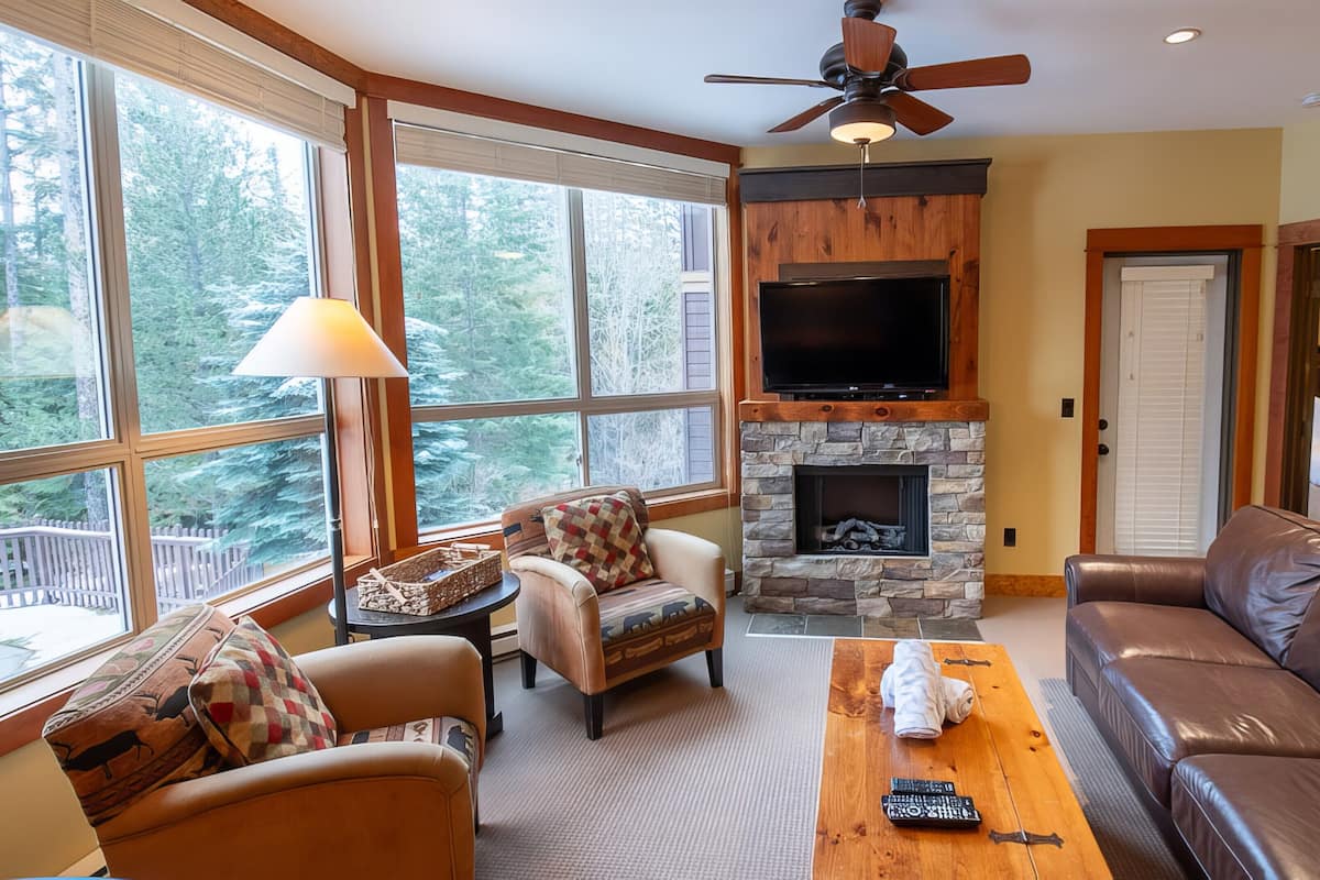 A cozy living room with a stone fireplace, leather sofa, and a television.