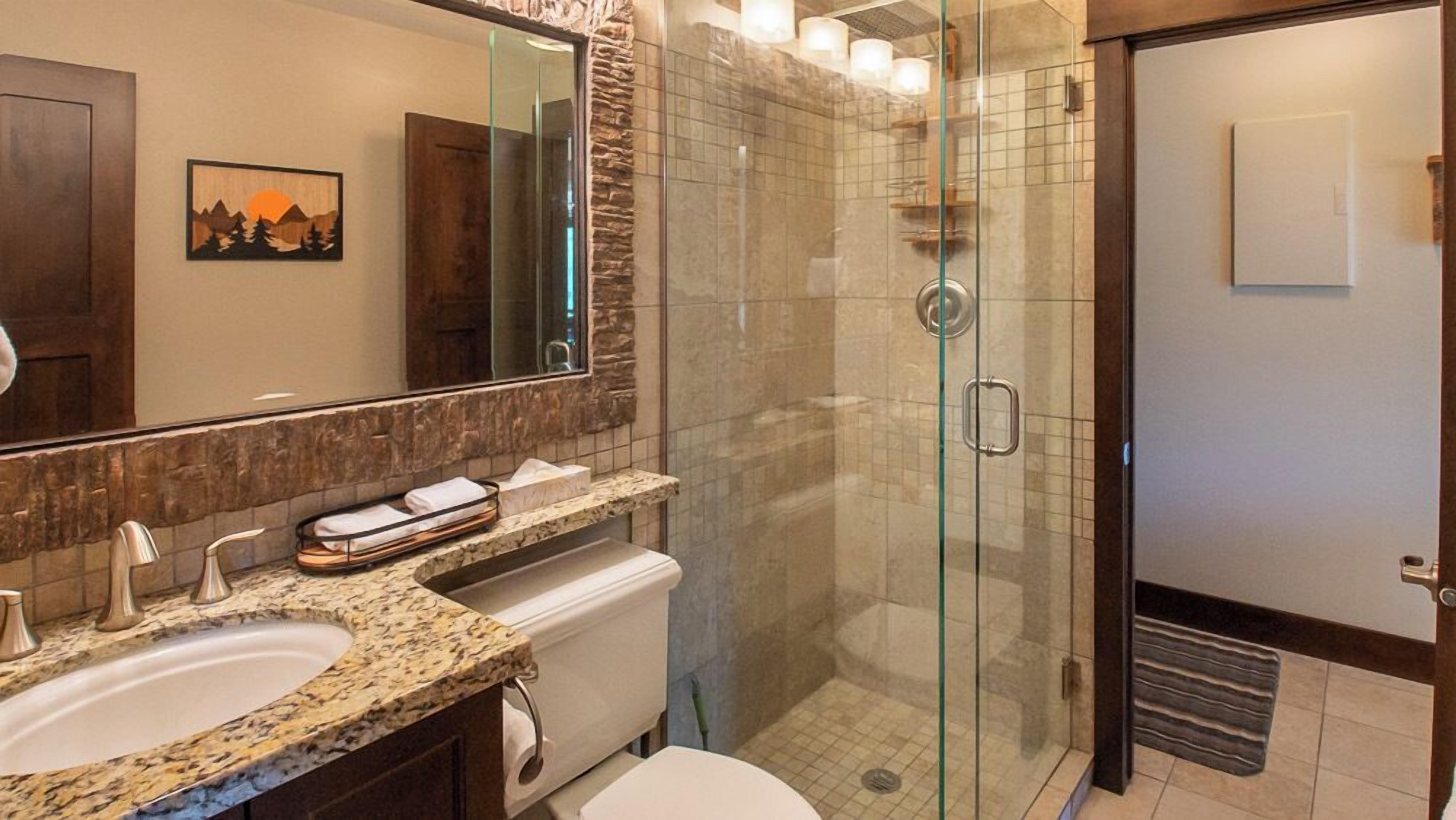 Une salle de bain moderne avec deux lavabos, une douche à l’italienne et un grand miroir.