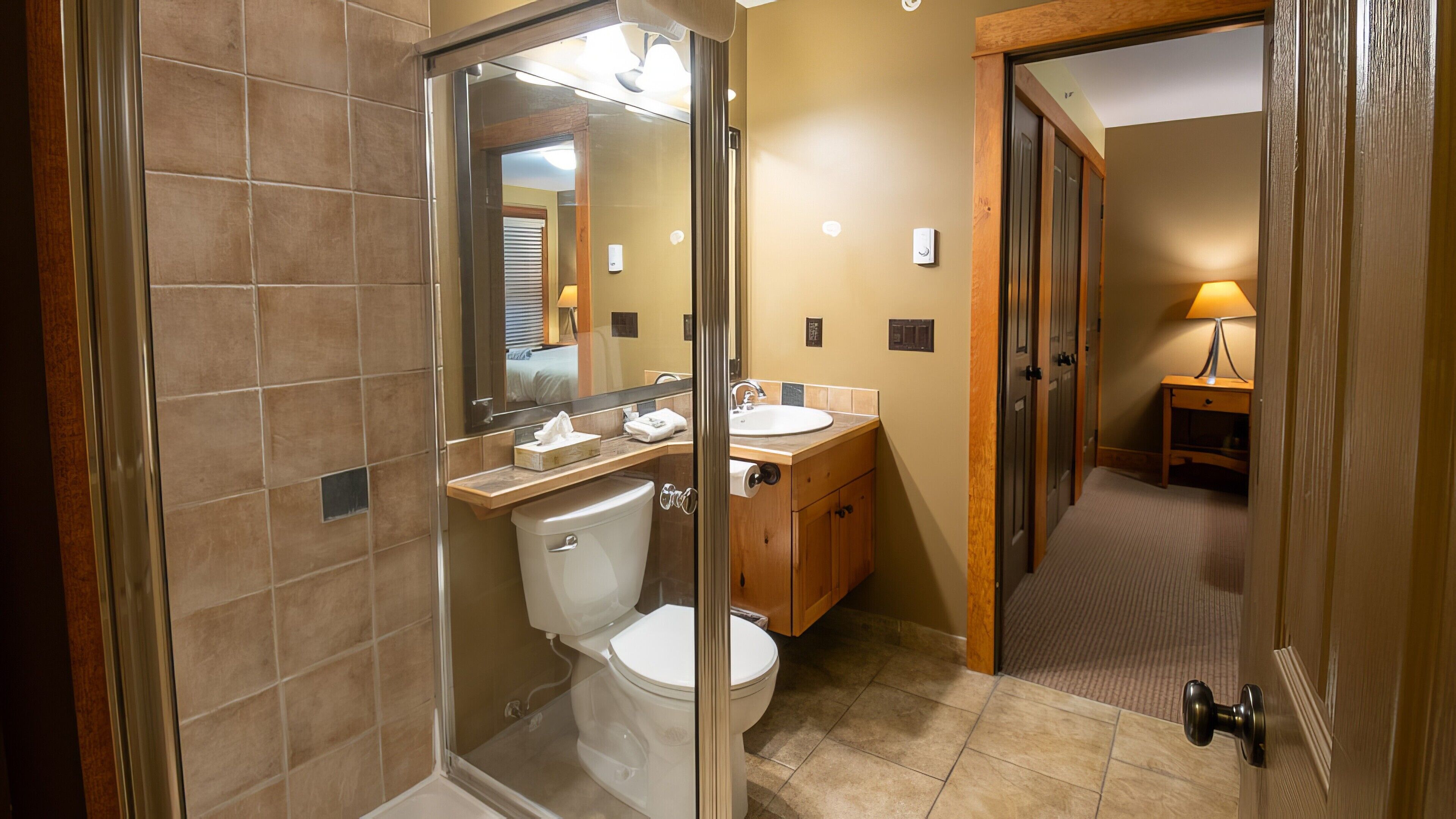 Une salle de bain moderne dotée d’une douche à parois de verre, de toilettes et d’un lavabo.